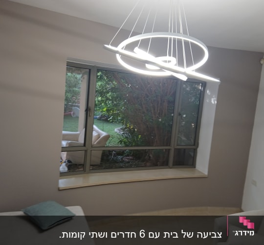 חדר עם קיר צבוע, חלון גדול ומנורה מודרנית
